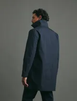 Gabardina clásica de corte recto, color beige, con cuello camisero, cierre frontal de botones y bolsillos laterales. Confeccionada en tejido técnico repelente al agua y al viento.