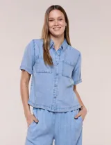 Camisa de corte recto y calce fluido color celeste, confeccionada en lyocell con efecto lavado, cuello camisero tradicional, botones a tono, dos bolsillos aplicados en el pecho y mangas cortas.