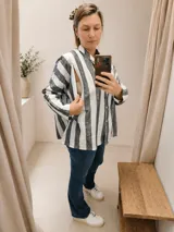 Camisa oversize de manga larga con estampado de rayas verticales en tonos gris y blanco. Presenta un diseño funcional con aberturas laterales con cierres invisibles, ideal para lactancia.