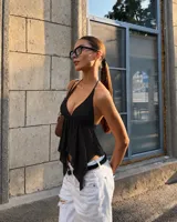 Top negro halter con escote en V pronunciado, tirantes finos para atar al cuello y diseño asimétrico con terminación en puntas.