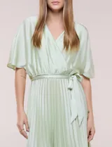 Vestido maxi de satén color rosado, con escote en V cruzado, mangas cortas amplias, cintura elastizada con lazo de ajuste y falda plisada con forro interno.