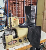 Bota de cuero negro con diseño 2 en 1, que incluye una polaina de gamuza desmontable. Presenta una base de bota de cuero liso y una caña alta de gamuza, ofreciendo versatilidad para diferentes estilos.