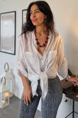 Camisa de seda blanca de corte holgado, con mangas tres cuartos con trabilla para arremangarlas, cuello camisero, cierre frontal con botones y dos bolsillos en el pecho.