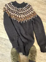 Sweater tejido a mano de corte clásico, color gris con diseño de guarda nórdica en el canesú en tonos blanco, marrón y detalles en rojo.