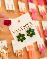 Par de aros tipo botón con forma de flor de cinco pétalos color verde esmeralda con centro dorado.