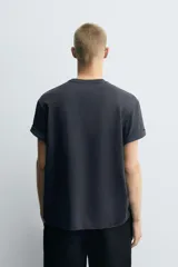 Camiseta azul marino de corte relaxed fit, cuello redondo y manga corta. Presenta un parche rectangular estampado con rayas horizontales rojas y blancas, y un dibujo de una langosta en el centro.