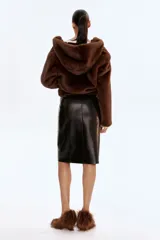 Pollera tubo de tiro alto confeccionada en tejido revestido con acabado efecto cuero. Presenta diseño de largo hasta la rodilla, bolsillos delanteros con cierre metálico y costuras verticales decorativas.