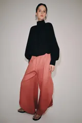 Pantalón confeccionado en lino 100%, de tiro medio con cintura elástica ajustable mediante cordones y bajo redondeado con aberturas laterales.
