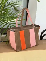 Bolso tipo shopper de diseño amplio, confeccionado en gamuza con un patrón de franjas verticales en tonos marrón oscuro, rosa y verde oliva. Cuenta con doble asa de hombro y cierre superior.