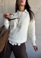 Sweater de punto color natural con diseño de flores bordadas en relieve, cuello redondo y puños acanalados. Presenta un corte clásico y versátil.