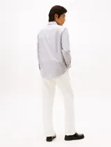 Camisa de manga larga para hombre, con cuello clásico y cierre de botones. Presenta un diseño de rayas verticales finas en tonos blanco y azul oscuro. Cuenta con el logo de Tommy Hilfiger bordado en el pecho.