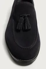 Mocasines de vestir para hombre confeccionados en piel con acabado en serraje de color azul marino, con detalle de borlas en el empeine y suela con ligero tacón.