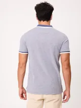 Remera polo de piqué de algodón melange color celeste, con cuello y puños en contraste blanco y azul, cierre frontal con botones y bordado pequeño en el pecho.