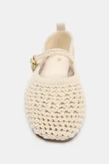 Zapatos planos tipo bailarina de color beige, confeccionados en tejido con efecto trenzado. Presentan una tira en el empeine con hebilla metálica dorada, tirador trasero y suela plana.