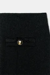 Pantalón de tiro medio confeccionado en tejido bouclé con hilos metalizados. Presenta pierna ancha, cintura elástica y falsos bolsillos de vivo decorados con botones dorados en la parte frontal.