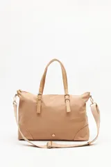 Cartera tipo tote de nylon color beige, con asas superiores fijas y correa larga ajustable y desmontable. Presenta herrajes metálicos dorados y detalles de tiras con hebillas en la parte frontal.