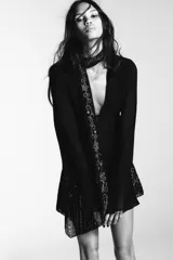 Camisa semitransparente negra de viscosa, con escote en pico pronunciado y manga larga con volantes. Incluye un foulard del mismo tejido con bordados florales y abalorios a contraste en tonos dorados y plateados.