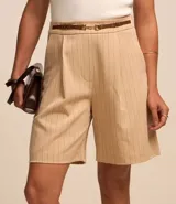 Bermuda sastrera color beige con estampa de raya de tiza, corte alargado, cinturón fino en la cintura y pliegues.