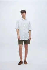 Camisa de manga corta a rayas verticales blancas y verdes, con cuello solapa clásico, bolsillo en el pecho y botones personalizados.