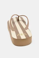 Sandalias tipo ojotas color marrón con plataforma gruesa a rayas horizontales blancas y marrones.