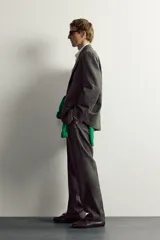 Pantalón de traje regular fit de la colección especial Aaron Levine x Zara, confeccionado en mezcla de lana y lino de color gris. Presenta diseño con pinzas delanteras, bolsillos laterales y traseros de doble vivo con botón, y cierre frontal con cremallera y gancho metálico oculto.