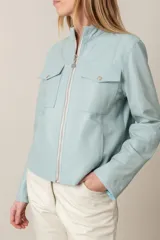 Campera celeste de cuero ovino italiano, con cuello mao, cierre metálico frontal, bolsillos laterales y bolsillos falsos con solapa y broches a la altura del busto.