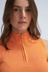 Top tejido color naranja, con cuello halter y cierre frontal parcial con cremallera.
