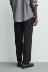 Pantalón de vestir regular fit color negro, confeccionado en tejido con mezcla de lana y elasticidad. Cuenta con cintura elástica, bolsillos frontales, bolsillos traseros de vivo con botón, y cierre frontal con cremallera y botón.