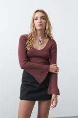 Top de tejido acanalado negro, con escote en V, mangas largas con terminación acampanada y ajuste al cuerpo.