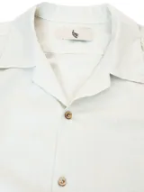 Camisa negra de manga corta con cuello camp y calce relajado. Confeccionada en una mezcla de lino y algodón, terminada con botones de madera y parche característico de Polonio. Hecha en Italia.