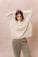 Buzo de calce relajado color beige, con cuello redondo, manga larga y recortes curvos decorativos con costuras a la vista en el frente. Terminaciones en puños y cintura.