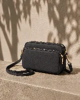 Cartera bandolera negra de nylon impermeable con tres compartimentos principales con cierre, herrajes dorados y correa ajustable desmontable.
