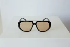 Lentes de sol con armazón de policarbonato negro y cristales tonalidad ámbar, con diseño de puente doble estilo aviador.
