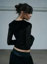 Camisa de encaje negro con cuello de piel sintética y cierre frontal con botones. Presenta mangas largas y un diseño ajustado al cuerpo.
