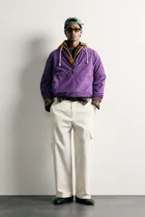 Chaqueta canguro técnica de corte relaxed fit en color violeta, con cuello subido ajustable, cierre frontal de cremallera parcial, manga larga y bolsillos frontales con cierre y tipo canguro.