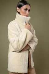 Campera tipo borrego de cuero con efecto desgastado, con interior y cuello de piel sintética en color crema. Presenta cierre frontal con botones a presión y bolsillos frontales amplios.