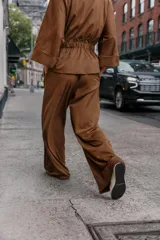 Pantalón de tiro alto color marrón, con cintura elástica ancha y pernera ancha, confeccionado en tejido con efecto ante o gamuza.