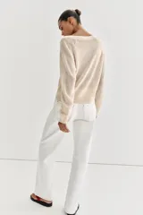 Jersey de punto color beige, con cuello redondo y cierre frontal parcial de botones, manga larga y acabados en rib.