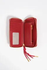 Billetera rígida de color negro con cierre de cremallera perimetral. Presenta el logo metálico de Bimba y Lola en color dorado en el frente y un tirador de cordón trenzado en tonos marrón y amarillo. El interior cuenta con compartimentos para tarjetas y un monedero con cierre.