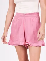 Short holgado color morado, con cintura fruncida y detalle de lazo o nudo en el frente. El ruedo tiene un ligero volante o volado.