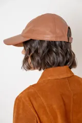 Gorra tipo baseball de cuero color negro, con bordado frontal que incluye un símbolo de flor de lis y la inscripción 'EST. 1994'.