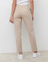 Pantalón jogger de algodón color beige, de tiro medio con pretina elastizada y bolsillos laterales, corte recto y relajado.