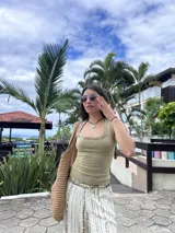 Musculosa verde oliva de morley, translúcida y elástica, con cuello redondo y detalles de costuras expuestas y pequeños dijes metálicos.