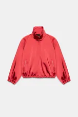 Cazadora roja de satén con cuello subido, manga larga con hombreras, bolsillos delanteros con cierre, bajo ajustable con cordón elástico y cierre frontal de cremallera metálica.