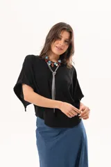 Blusa de silueta relajada y caída fluida, color negro, con escote redondo y mangas amplias.