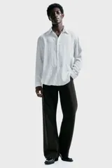 Camisa blanca de manga larga con rayas verticales finas en gris, cuello inglés, tapeta clásica de botones y bajo redondeado.