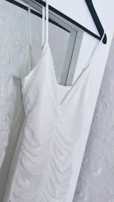 Vestido blanco de breteles finos, con escote en V y falda midi con volados.