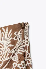 Short de tiro alto con detalle de nudo delantero y bordados florales perforados.