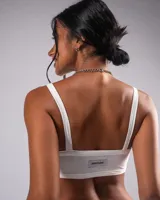 Top crop blanco de tirantes anchos, con escote recto y detalle de strass en el frente con el texto "Javastudio".