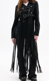 Campera corta estilo biker confeccionada en cuero sintético, con cierre frontal asimétrico, solapas anchas y cinturón ajustable en la cintura. Presenta un diseño distintivo con flecos largos que caen desde el dobladillo, aportando movimiento y un estilo bohemio.